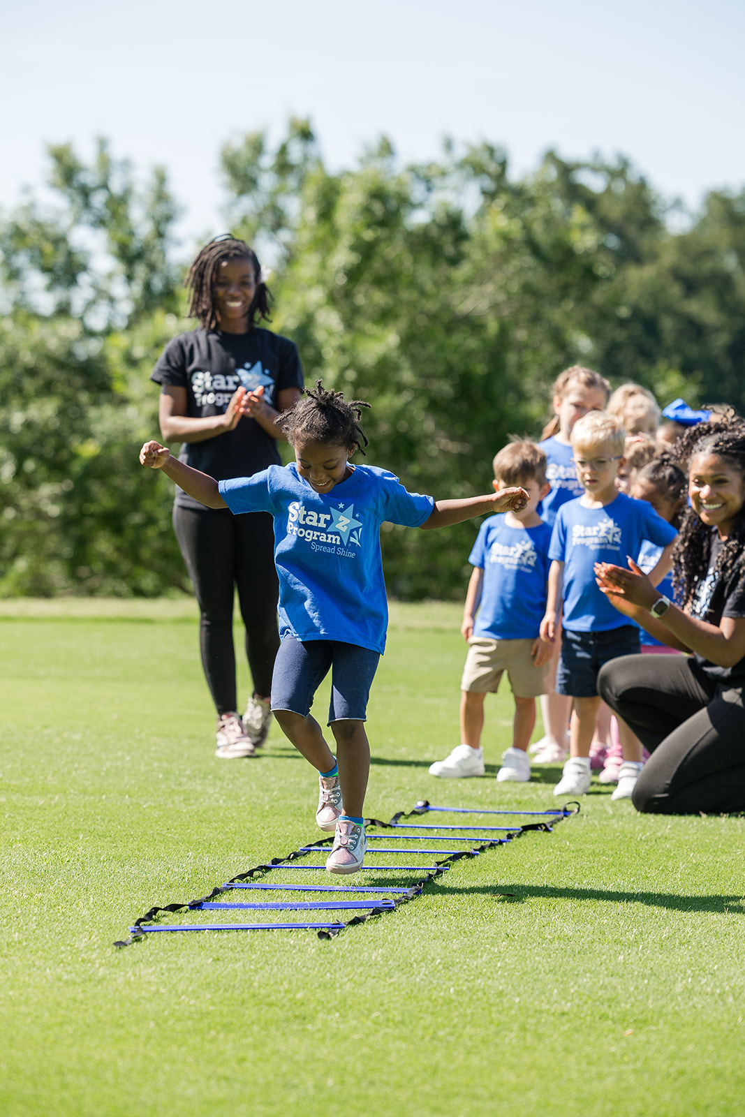 Child jumping through an agility ladder at Ninja Fitness class